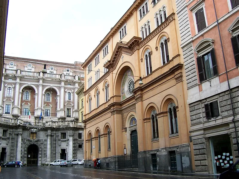 Valdenský kostel na Via Quattro Novembre v Římě pohledem z ulice, okrová budova s obloukovými okny a křížem nad mozaikovým obloukem.
