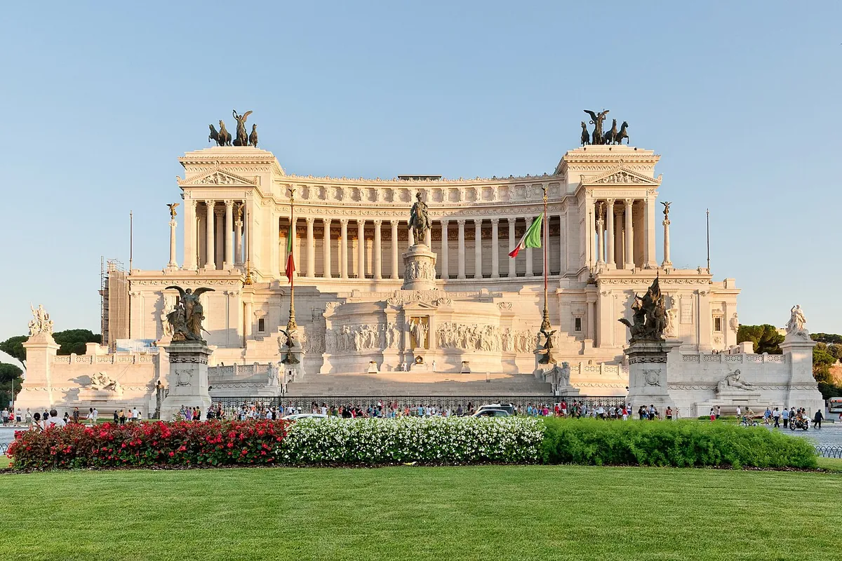 Bílý mramorový Vittoriano, Altare della Patria, na Piazza Venezia v Římě, s bronzovými skupinami vozů na střeše a květinovými záhony vpředu.